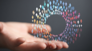 A hand holding a circle of colorful digital people icons representing audience targeting.